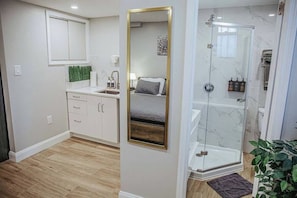 Een moderne badkamer met een douchecabine van glas, een grote spiegel en een toilet.