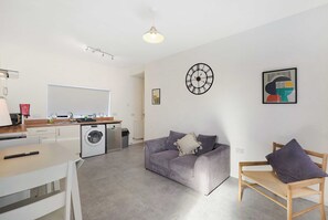 Een moderne woonruimte met een keuken, een eethoek en een zithoek met een bank en een fauteuil.
