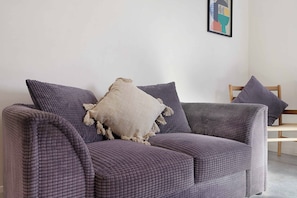 A modern living room with a sofa and a chair, a framed abstract artwork on the wall, and a concrete floor. - Chic 1BR Stay near Darlington | Sleeps 2 | TV+WiFi (Darlington)
