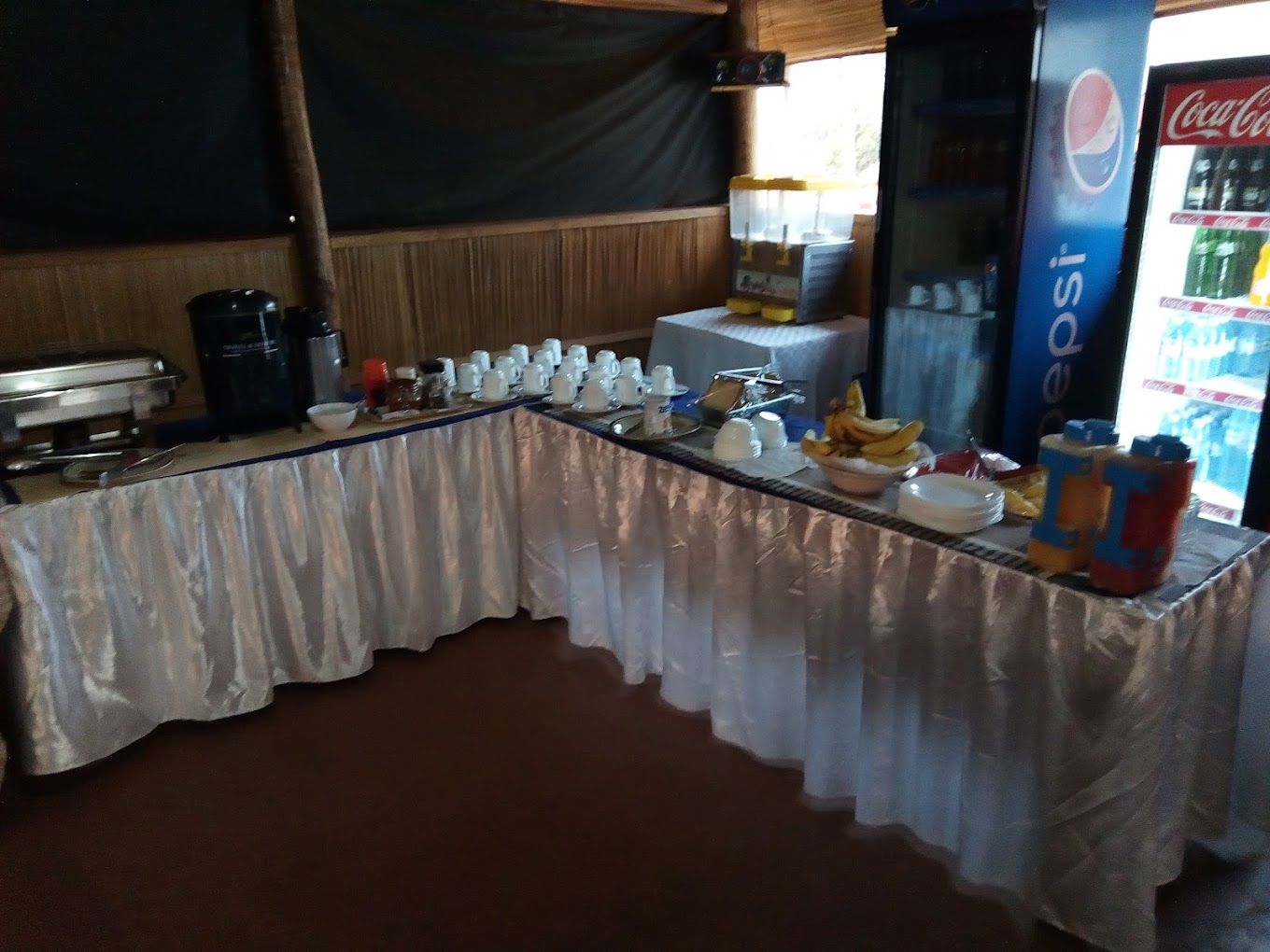 A buffet setup with a variety of food items and beverages, including a Pepsi refrigerator.