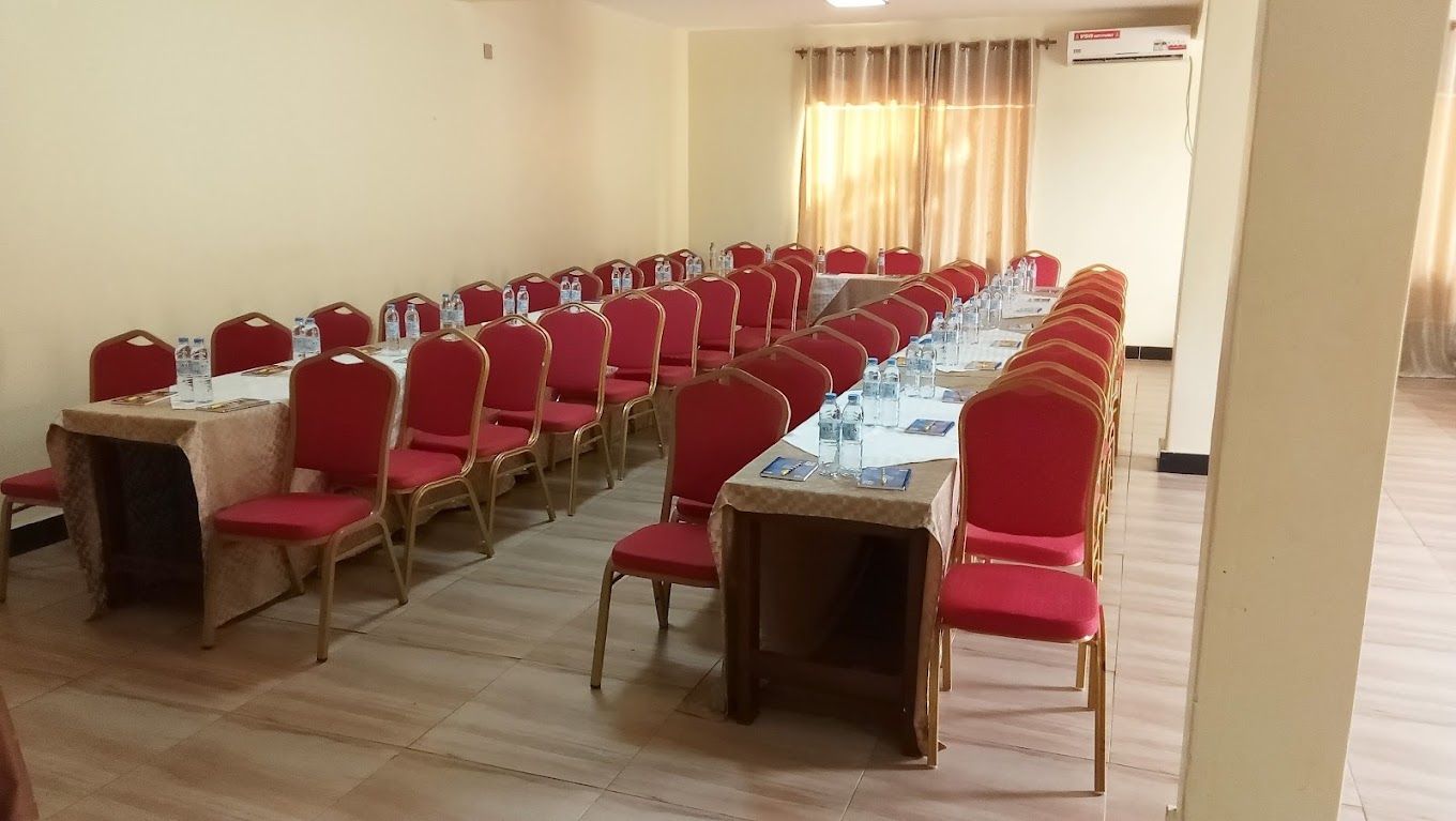 Un salón de conferencias con filas de mesas y sillas, equipado con botellas de agua y tarjetas de identificación.