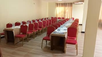 Un salón de conferencias con filas de mesas y sillas, equipado con botellas de agua y tarjetas de identificación.