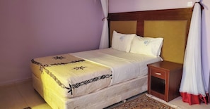 Una cama con cabecera, una mesita de noche y una alfombra estampada.