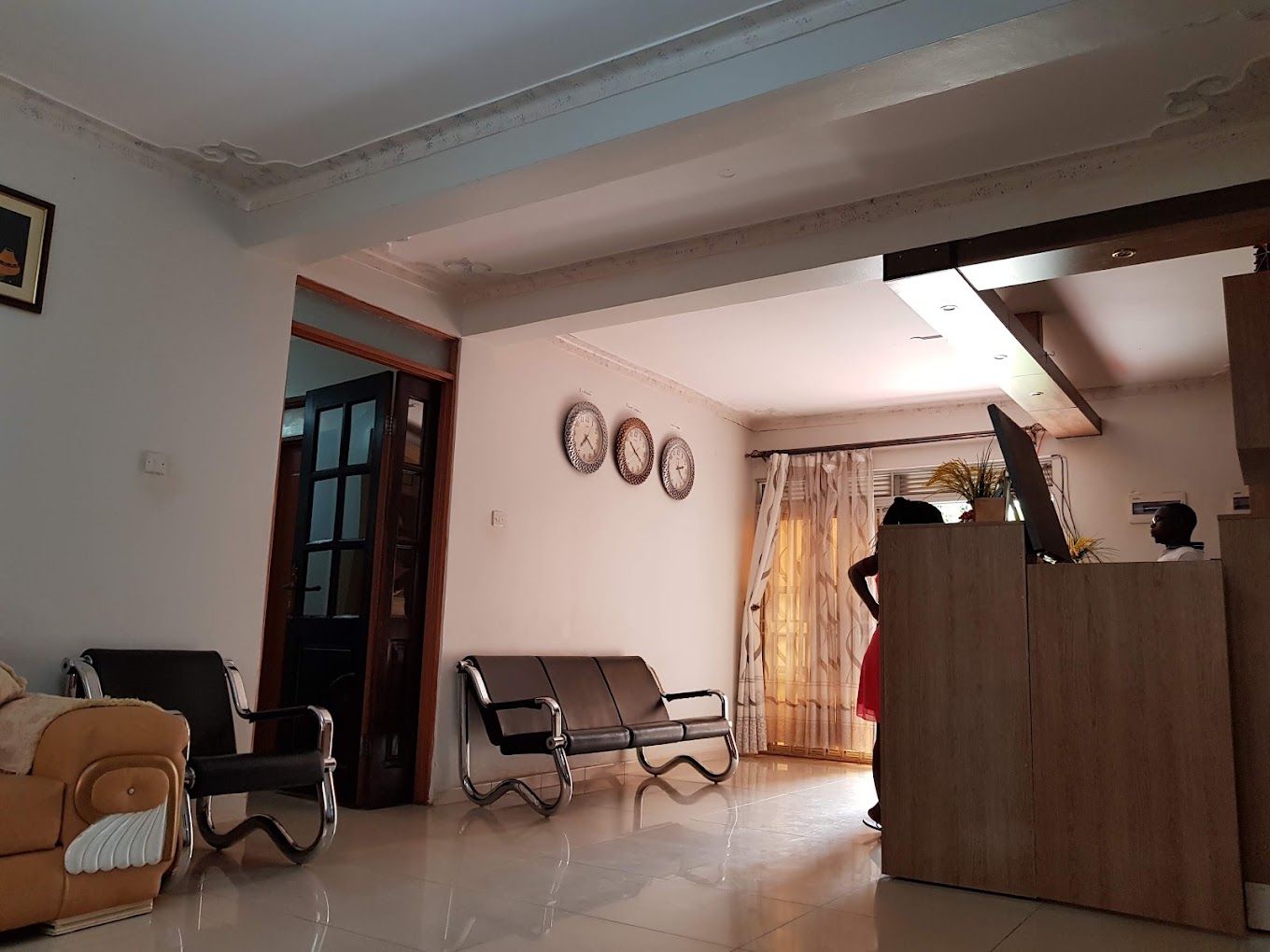 A living room with a sofa, a bench, a wooden cabinet, and a door leading to another room.