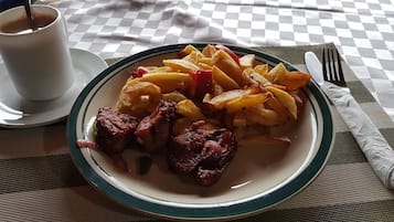 Un plato de comida con papas fritas, una taza de café y un tenedor sobre una mesa.