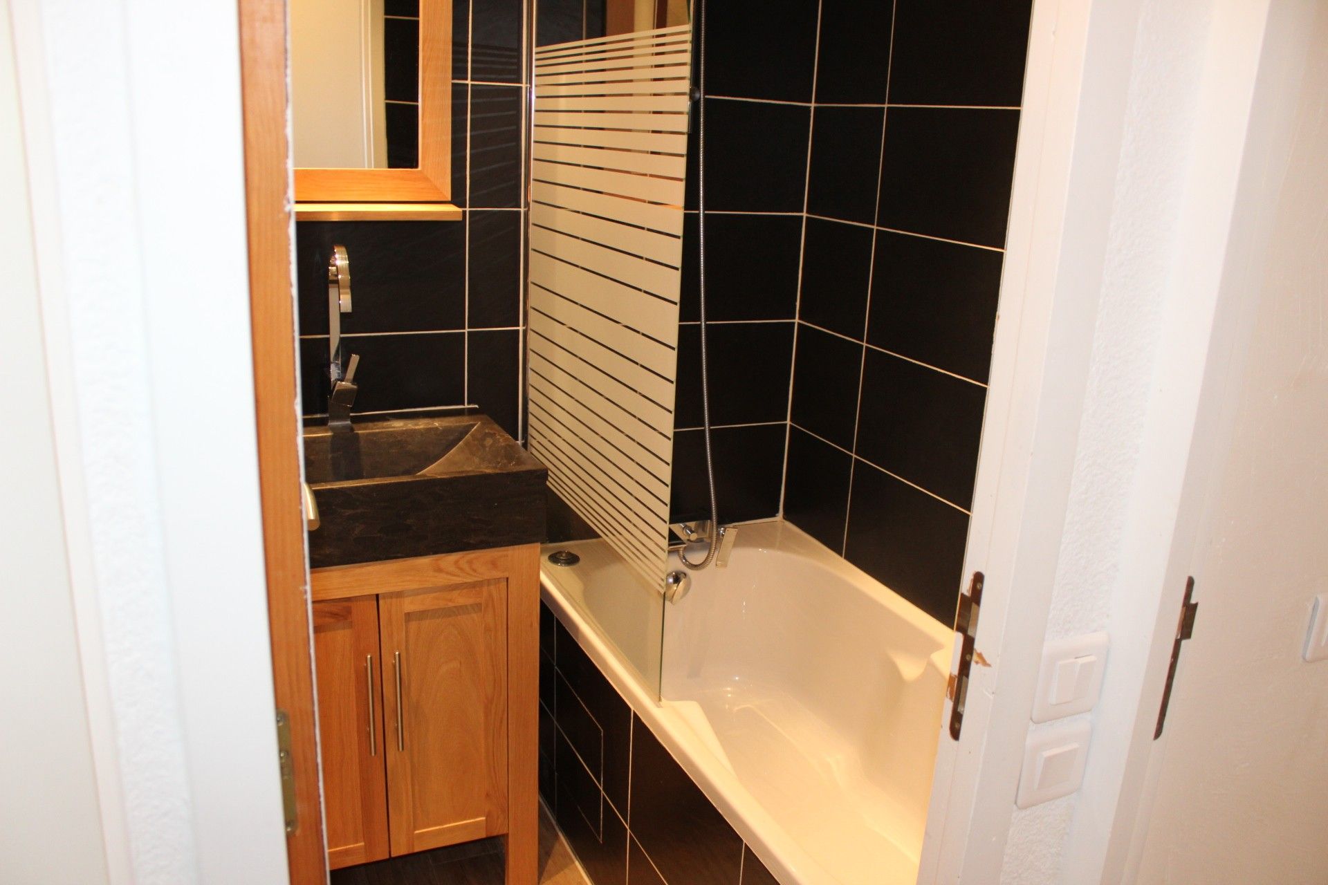 A bathroom with a bathtub, a sink, and a mirror.