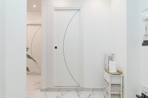 A hallway with a white door, a radiator, and a small white cabinet with drawers. - Maison Tresor by Wonderful Italy (Turin)