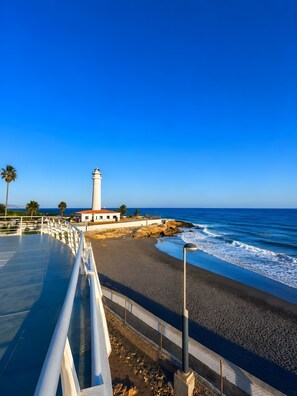 A coastal scene with a white lighthouse, a beach, and a clear blue sky. - Apartment 'La Canoa 79' with Sea Views, Wi-Fi and Air Conditioning (Torrox)