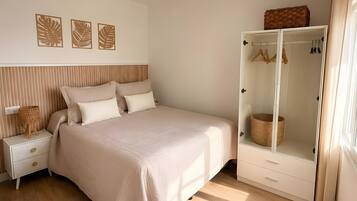 Een slaapkamer met een bed, nachtkastje, kledingkast en wanddecoratie.