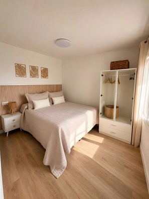 Een slaapkamer met een bed, nachtkastje, kledingkast en wanddecoratie.