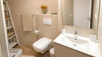 Een moderne badkamer met toilet, wastafel en douche.