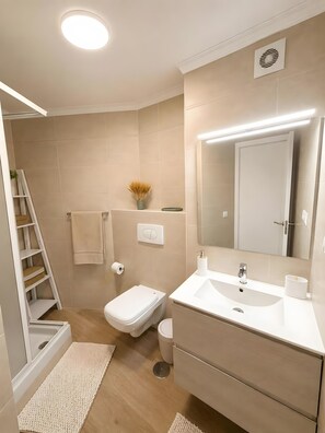 Een moderne badkamer met toilet, wastafel en douche.