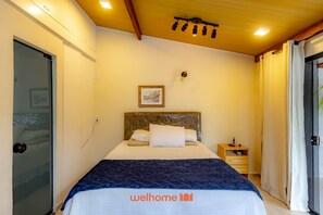 A well-lit bedroom with a bed, a bedside table, and a door. - Casa em Navegantes com Piscina Proximo a Praia (Navegantes)