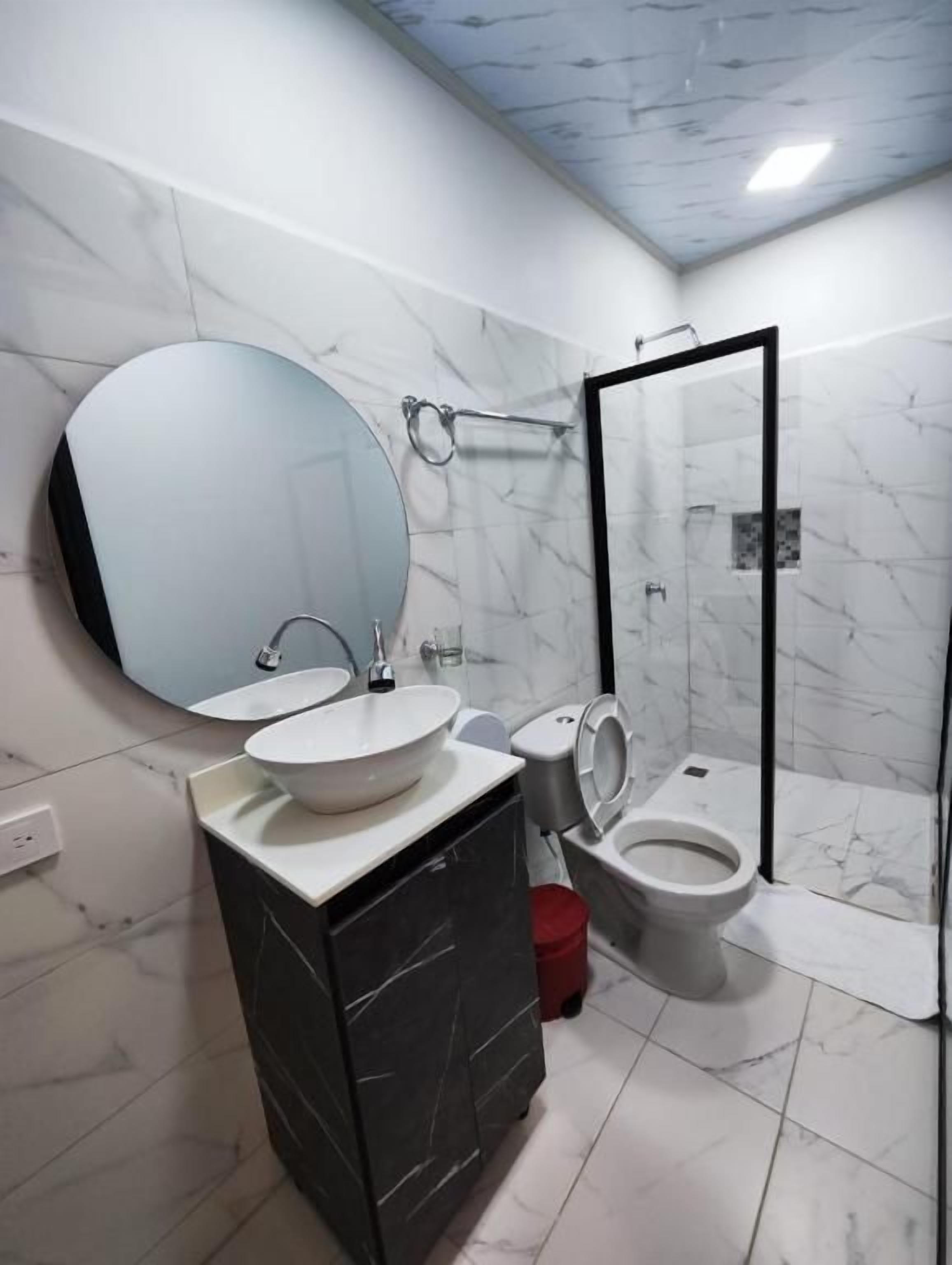 Un baño con inodoro, bidé y un espejo grande.