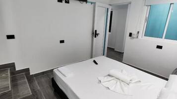 Una habitación de hotel con una cama, televisión, ventana y puerta.