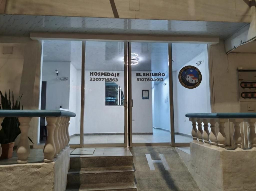 Fachada de un hotel con puertas de vidrio, una escalera y un mostrador de recepción.