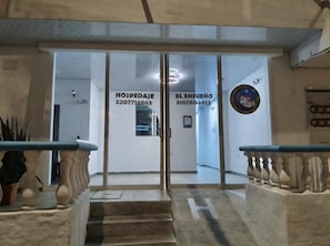 Entrada d'hotel amb portes de vidre, una escala i una recepció.