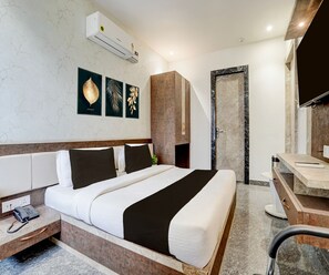 Ein Hotelzimmer mit Bett, Nachttisch, Telefon, Kunstwerk, Schrank und einem Badezimmer mit Spiegel und Waschbecken.
