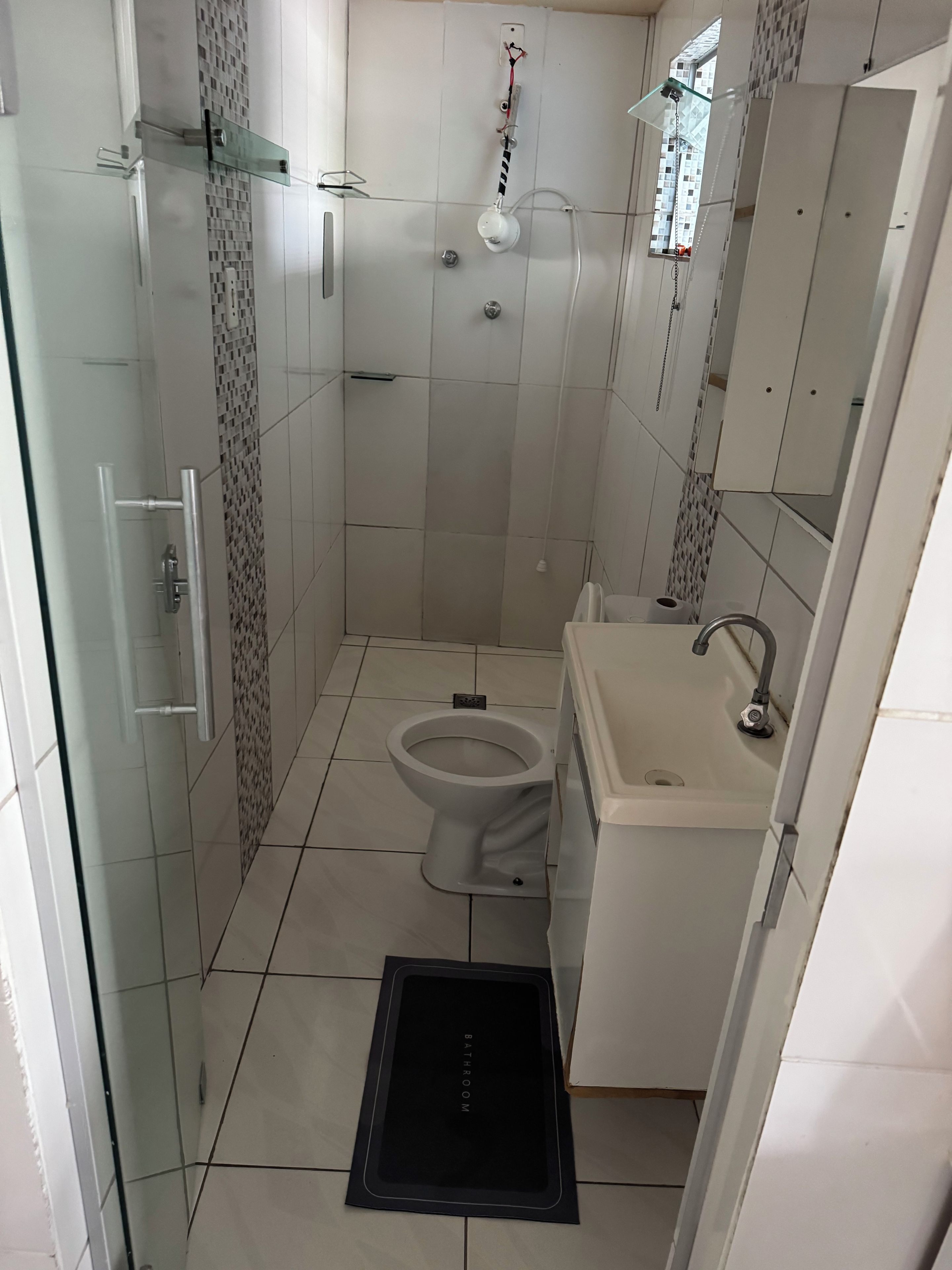 A bathroom with a toilet, sink, and shower area.