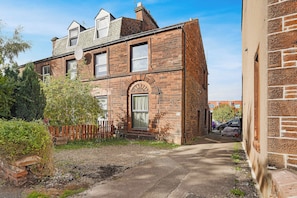 A two-story brick building with a visible window and a door, surrounded by a gravel path and a wooden fence. - Serene 2BR Stay in Penrith | Sleeps 4+Parking+WiFi (Penrith)