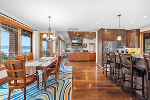 A spacious dining area with a long wooden table and chairs, a colorful rug, and a view of the outdoors. - Lakeview Retreat - 4BR Home (Somers)