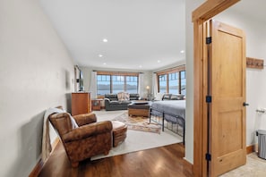 A spacious bedroom with a large bed, a sitting area with a sofa and armchairs, a wooden wardrobe, and a view of the outdoors through the windows. - Lakeview Retreat - 4BR Home (Somers)