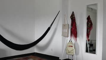 Una habitación con una hamaca, un bolso colgante y un espejo que refleja un papel tapiz estampado.