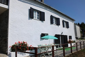 A white building with black shutters, a table with chairs, and a green umbrella. - Holiday Home 'Noninha House' with Mountain View, Shared Terrace and Wi-Fi (Alvarenga)
