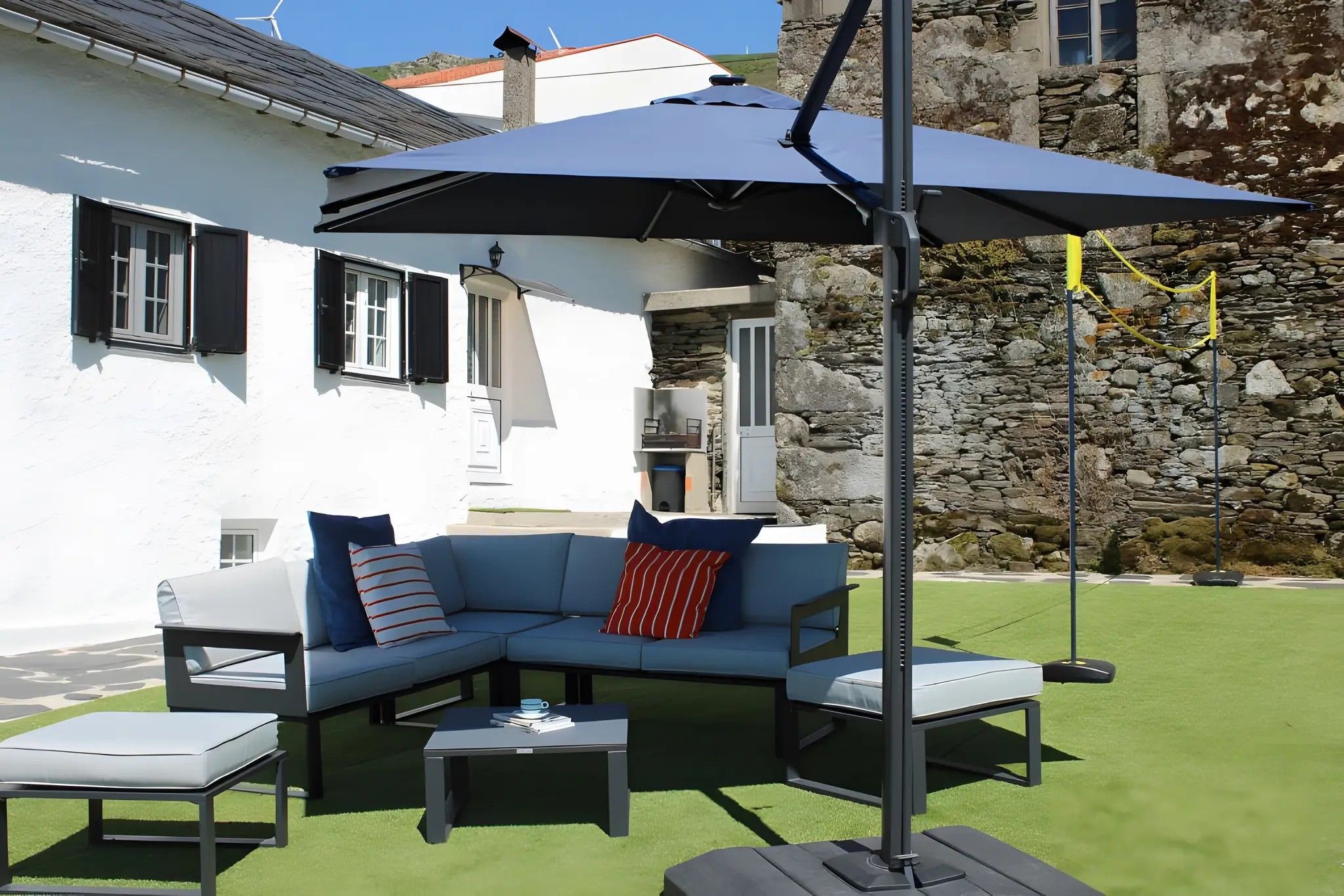 En terrasse med en hjørnesofa, to sofaborde og en stor parasol.