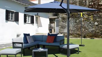 En terrasse med en hjørnesofa, to sofaborde og en stor parasol.