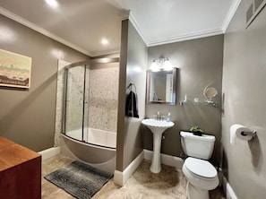Un bagno con una vasca freestanding, un lavabo su piedistallo, un water e un box doccia.