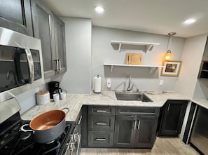 Una cucina moderna con elettrodomestici in acciaio inossidabile, un piano di lavoro in granito e mobili scuri.
