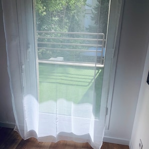 A room with a sliding glass door leading to a green outdoor area. - New Listing (Nîmes)