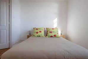A bedroom with a bed, two nightstands, and a door.
