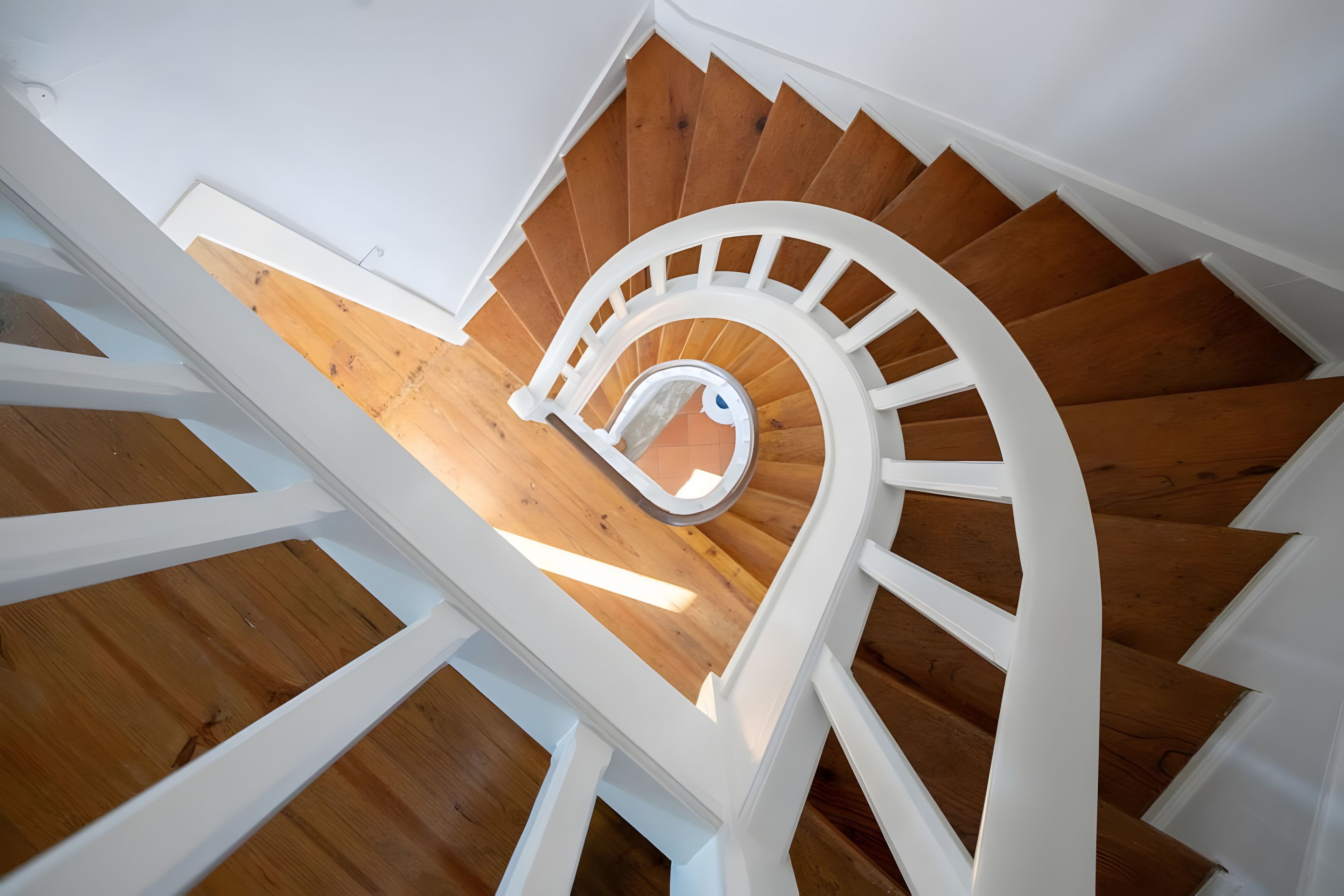 A spiral staircase with wooden steps and white railings.