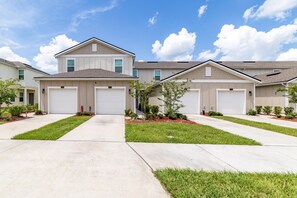 A residential building with a symmetrical facade, two garage doors, and a central entrance. - Modern 3BR Townhome | 30-Day Minimum (Jacksonville)