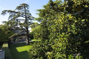 A well-maintained garden with a variety of trees and shrubs, a neatly trimmed lawn, and a building in the background. - Apartment 'Dama' with Private Terrace, Wi-Fi and Air Conditioning (Bardolino)