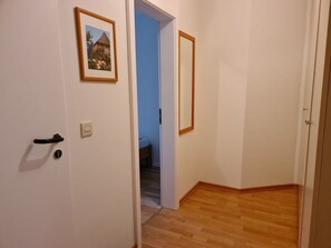 A hallway with a wooden floor, a door with a black handle, and a framed picture on the wall. - 12 / Waldstrasse (Wyk auf Foehr)