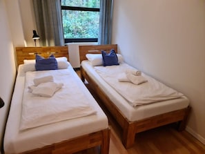 Two single beds with wooden frames, white bedding, and blue pillows. - 12 / Waldstrasse (Wyk auf Foehr)