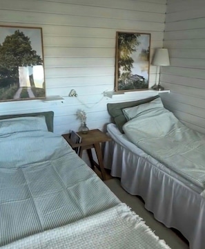A room with two single beds, a small table, and a lamp. - Cottage by Lake Ralången with alpacas and horses (Aneby)