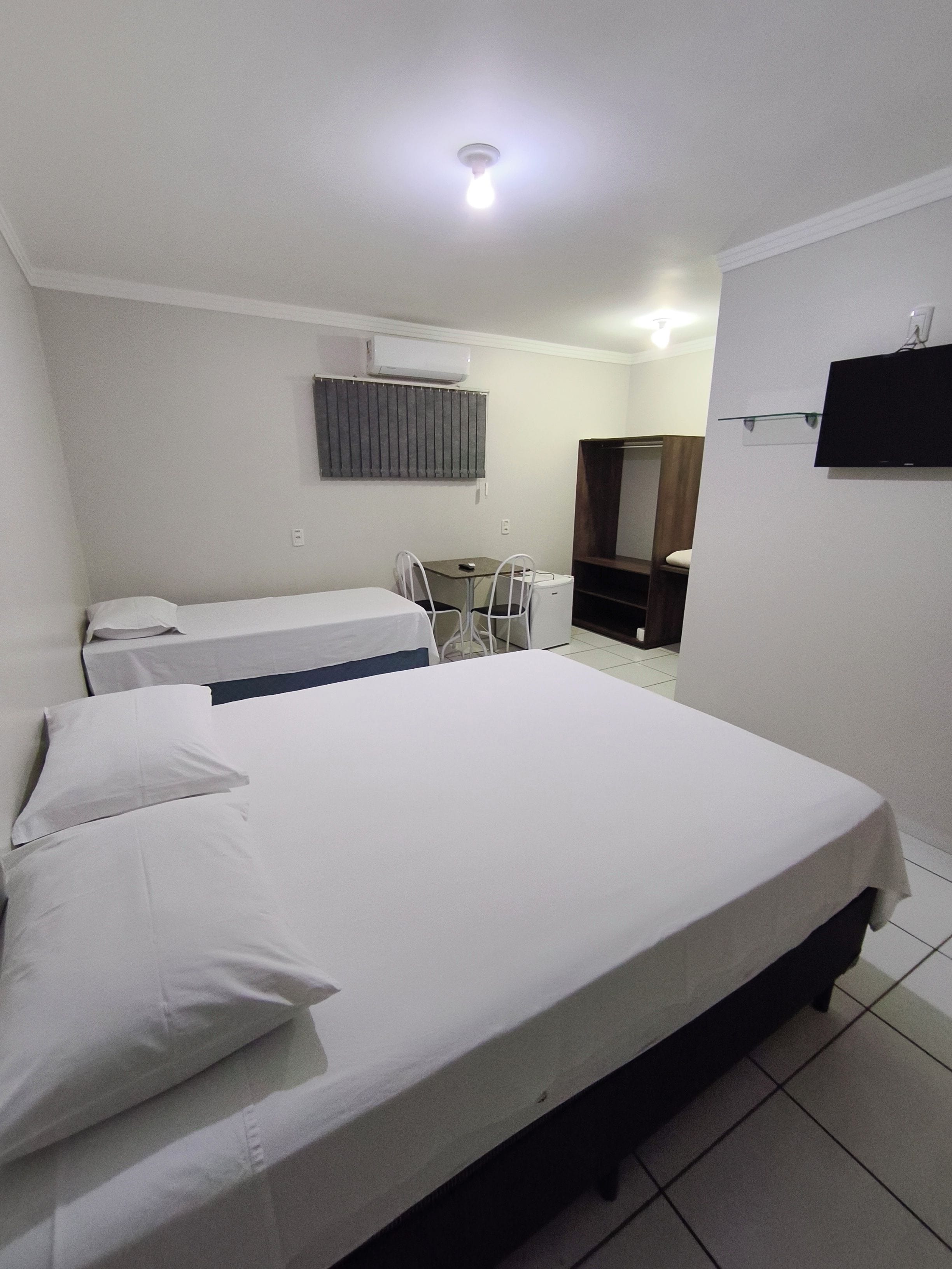 Une chambre d’hôtel équipée d’un lit, d’un bureau, d’une chaise, d’une télévision et d’un appareil de climatisation.