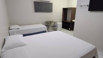 Une chambre d’hôtel équipée d’un lit, d’un bureau, d’une chaise, d’une télévision et d’un appareil de climatisation.