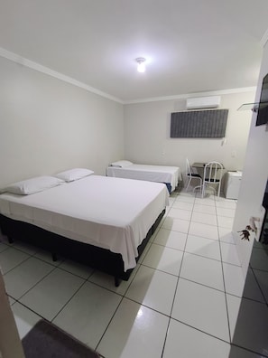 A hotel room with two beds, a desk, a chair, and a television. - Hotel Flor de Ipê (Sorriso)