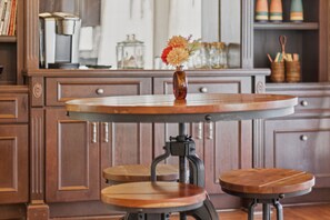 Een keuken met een ronde tafel op een standaard, houten stoelen en kastjes.
