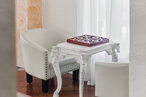 A white armchair and a small white table with a book on it. - La Amante Del Verano a Luxury Spanish-Style Retreat with Pool that Sleeps 15 (Lakeland)