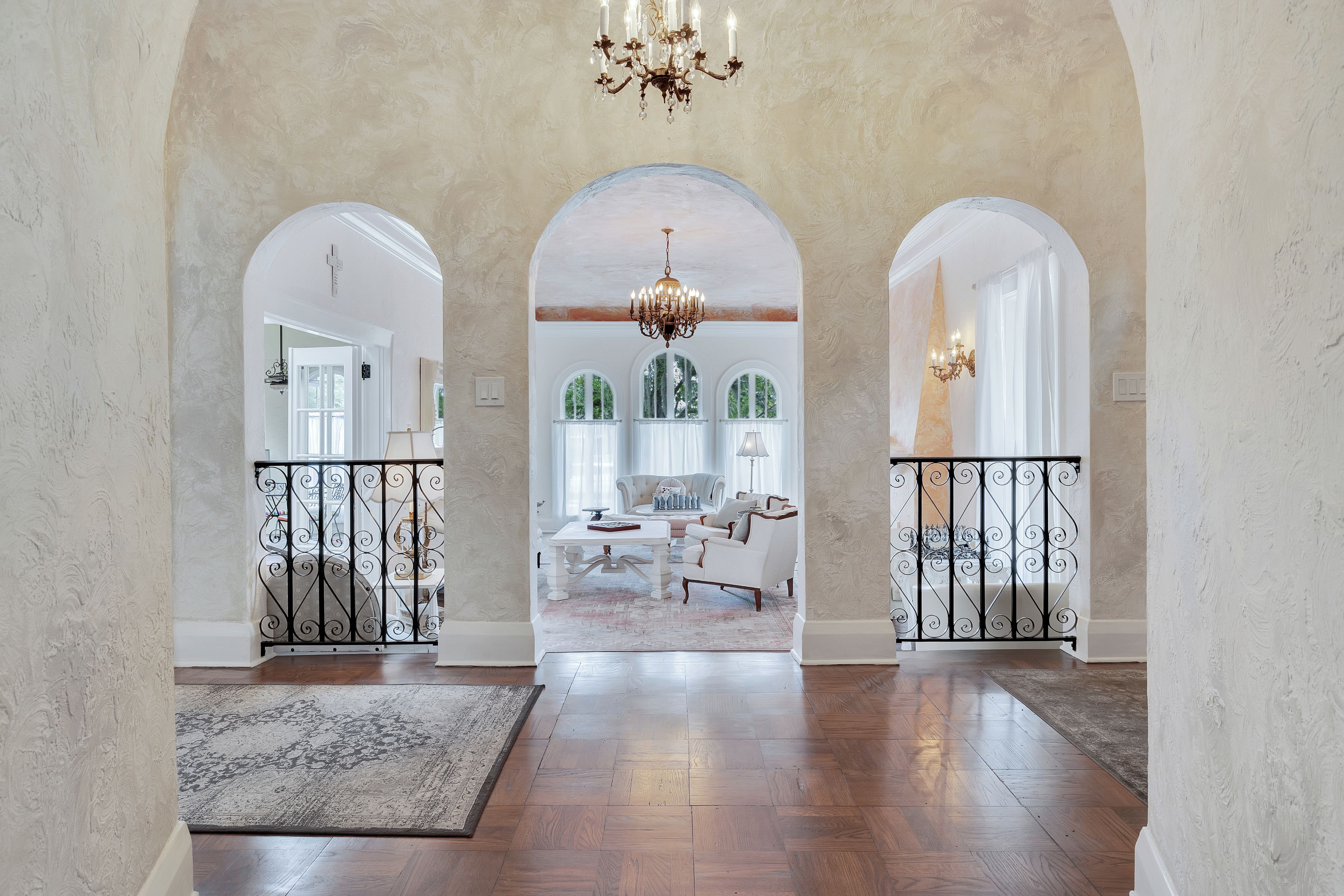 A spacious foyer with a high ceiling, a chandelier, and a view into a dining area.