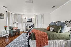 A bedroom with a bed, a chair, a fireplace, and a window with curtains. - La Amante Del Verano a Luxury Spanish-Style Retreat with Pool that Sleeps 15 (Lakeland)