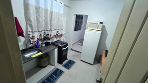 Una cuina compacta amb un rentatge, fogó, microones i nevera.