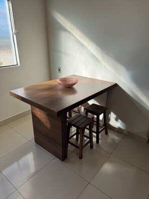 A kitchen with a wooden island, two stools, and a window.