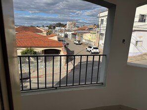 Un balcó amb vista a un carrer flanquejat per edificis, alguns amb teulades vermelles.